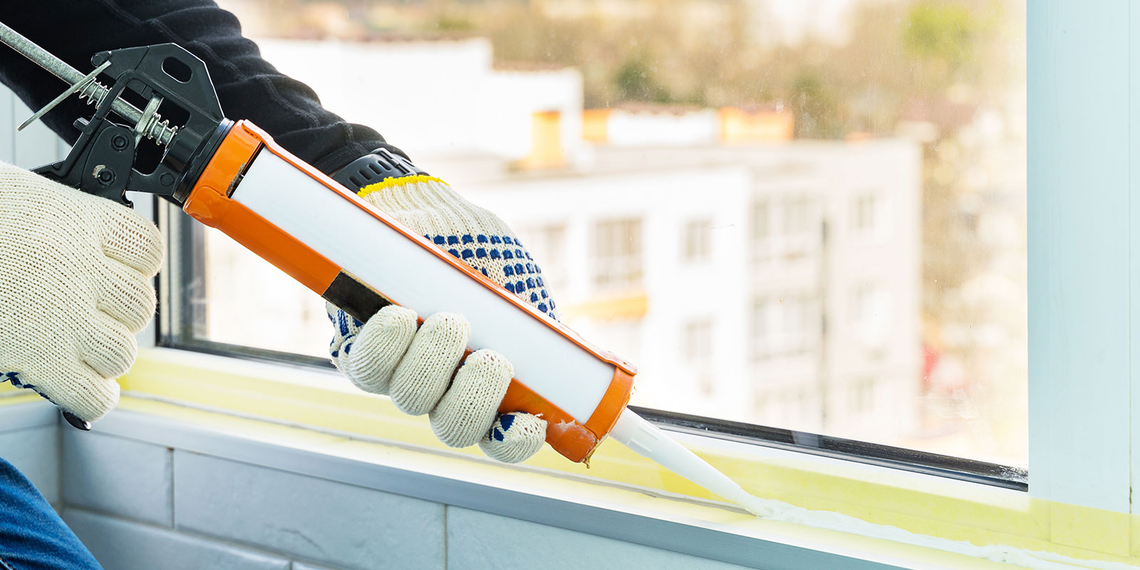 waterproof caulking a window with gloves on